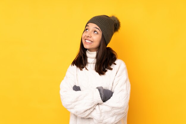 Mujer joven con sombrero de invierno mirando hacia arriba mientras sonríe