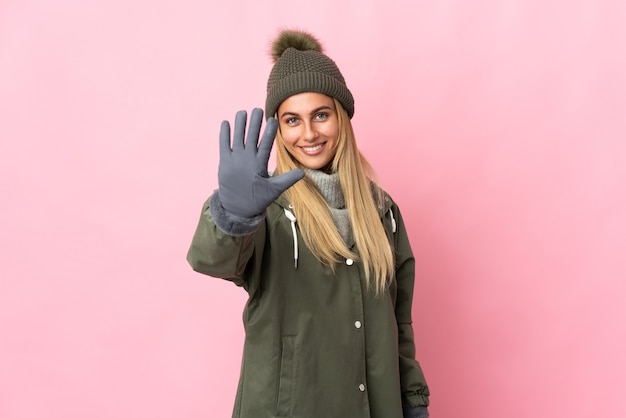 Mujer joven con sombrero de invierno posando aislado contra la pared en blanco