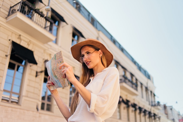Mujer joven con sombrero mirando el mapa de la ciudad
