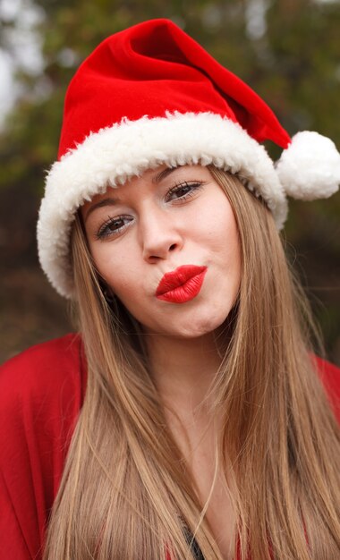 Mujer joven con sombrero de Navidad en el bosque