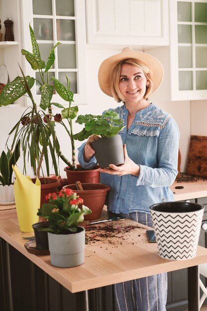 Mujer joven con sombrero de paja se dedican al cultivo y plantación de flores caseras