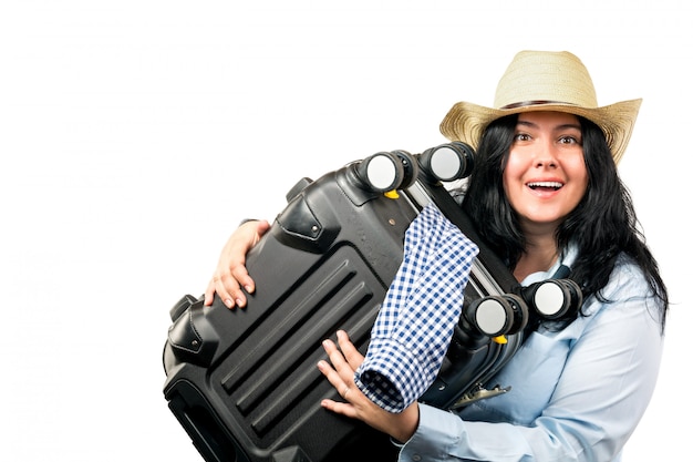 mujer joven con sombrero de paja sonriendo y sosteniendo la maleta