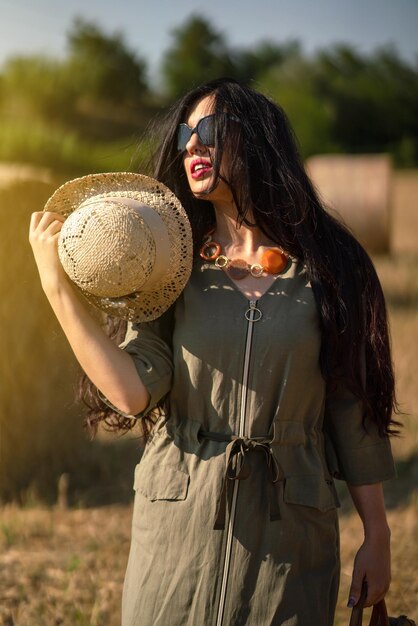 Foto mujer joven con sombrero de pie en el campo