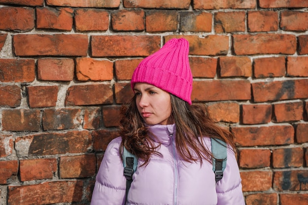 Una mujer joven con un sombrero rosa sobre un fondo de pared de ladrillo, retrato