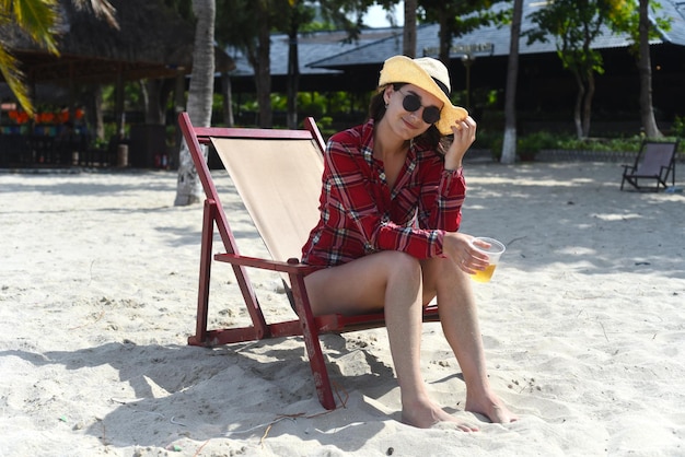 Mujer joven con sombrero sentada en la silla del escritorio en la playa con arena blanca en Vietnam