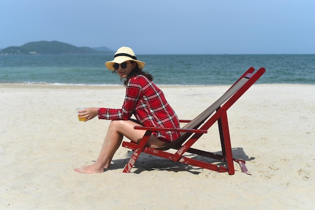 Mujer joven con sombrero sentada en la silla del escritorio en la playa con arena blanca en Vietnam