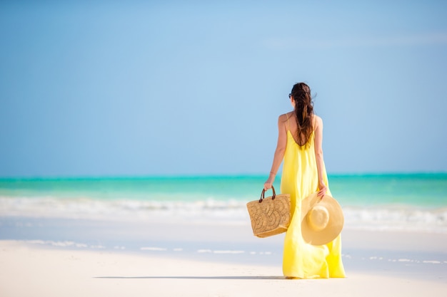 Mujer joven con sombrero durante vacaciones en la playa tropical