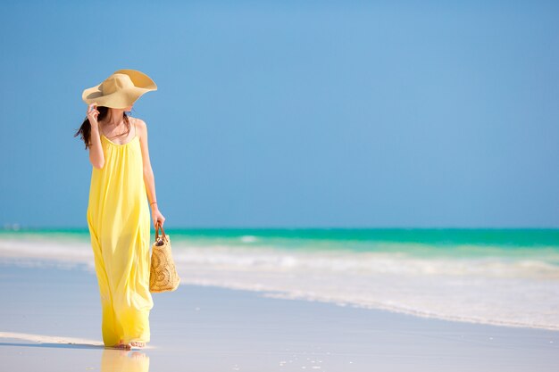 Mujer joven con sombrero durante vacaciones en la playa tropical