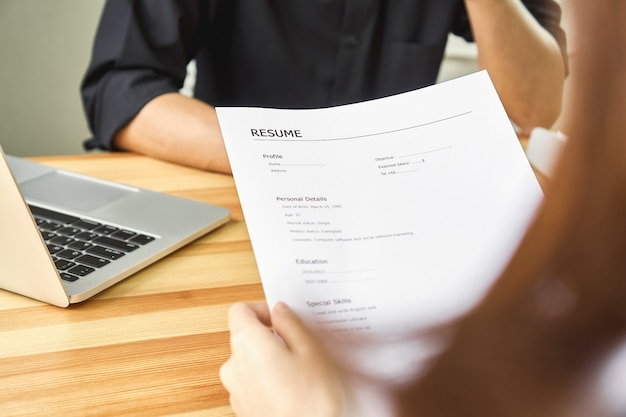 La mujer joven somete el curriculum vitae al patrón para repasar la aplicación de trabajo. El concepto presenta la capacidad de la empresa para estar de acuerdo con la posición del trabajo.