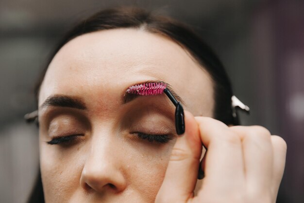 Una mujer joven se somete a un procedimiento de corrección de cejas en un salón de belleza. La niña pinta sus cejas en el salón.