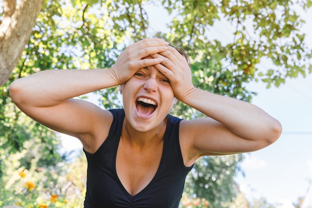 Mujer joven sonriendo al aire libre. Hermosa chica brunete descansando sobre fondo verde parque o jardín.