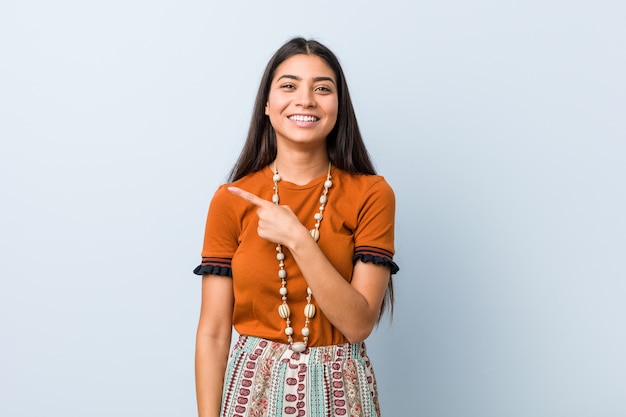 Mujer joven sonriendo y apuntando hacia el lado