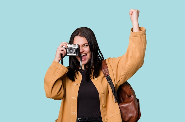 Mujer joven sonriendo con una cámara de cine mirando a través del visor emocionada por una nueva pasión