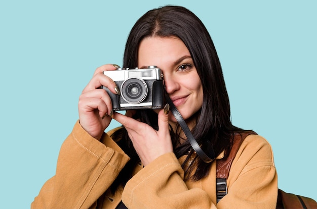 Mujer joven sonriendo con una cámara de cine mirando a través del visor emocionada por una nueva pasión