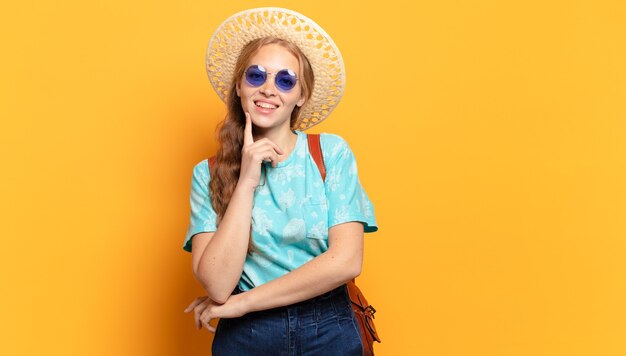 Mujer joven sonriendo felizmente y soñando despierto o dudando, mirando hacia el lado