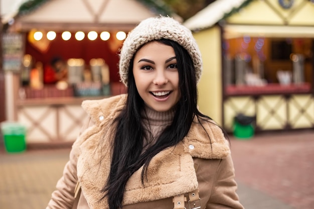 Mujer joven sonriendo mientras está de pie en la feria de vacaciones de invierno