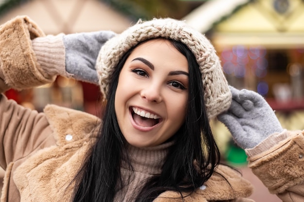 Mujer joven sonriendo mientras está de pie en la feria de vacaciones de invierno