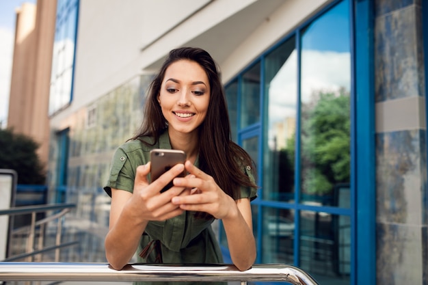 Mujer joven sonriendo mientras mira su teléfono inteligente