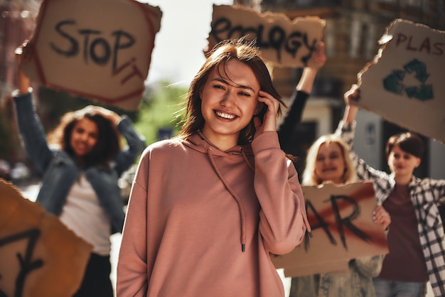 Mujer joven sonriendo mientras protestaba por la ecología con un grupo de activistas en la carretera