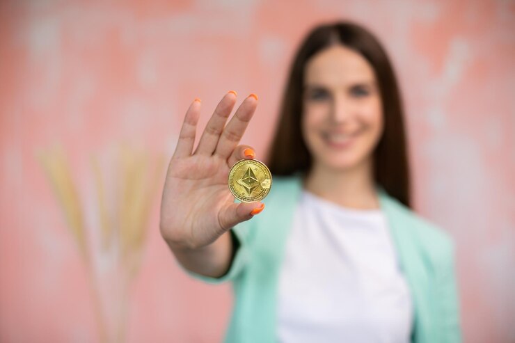 Mujer joven sonriendo sosteniendo criptomonedas como pago electrónico sobre fondo rosa