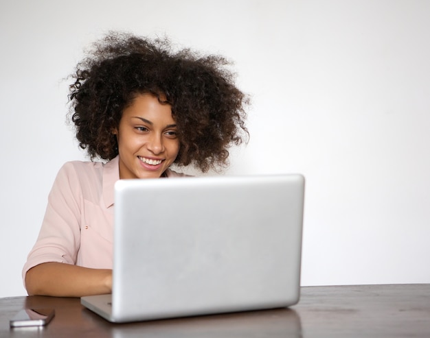 Mujer joven sonriendo y trabajando en la computadora portátil