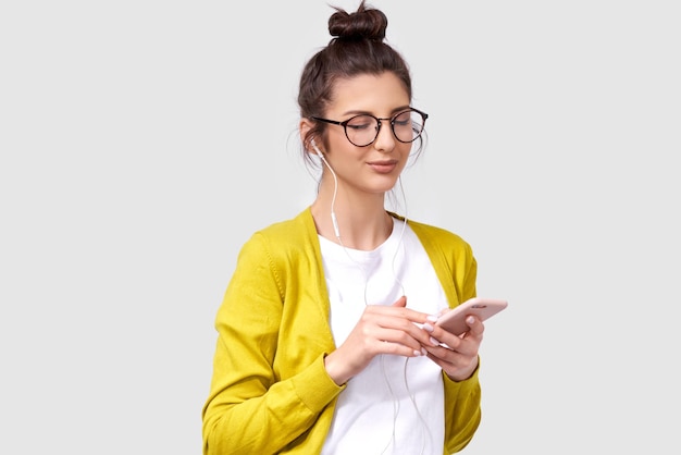 Mujer joven sonriente bastante morena usando el teléfono celular disfrutando de la música con los ojos cerrados Mujer feliz charlando con su novio a través de un teléfono inteligente Gente tecnología emociones humanas reales