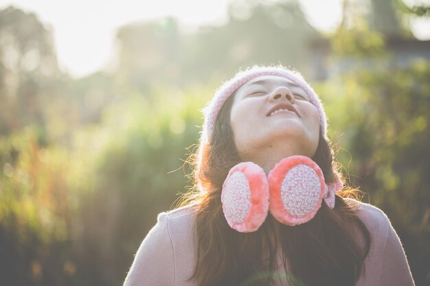 Foto mujer joven sonriente con la cabeza contra los árboles