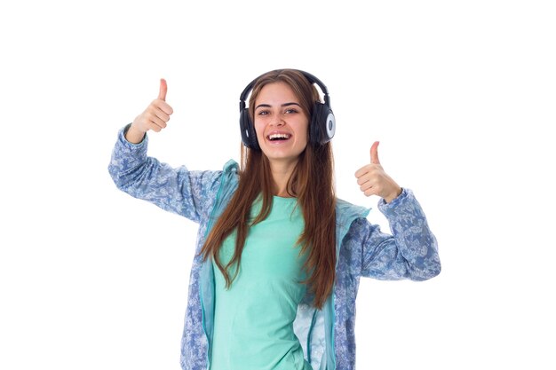 Mujer joven sonriente con camisa azul escuchando música con auriculares negros en el estudio