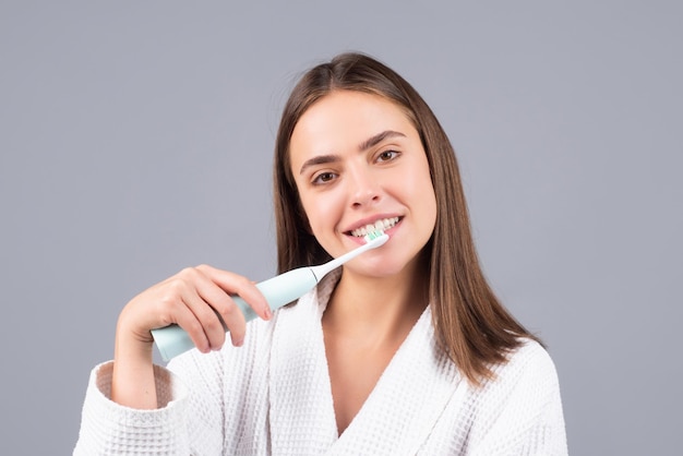 Mujer joven sonriente cepillarse los dientes con cepillo de dientes con pasta de dientes blanqueadora limpiar los dientes por la mañana