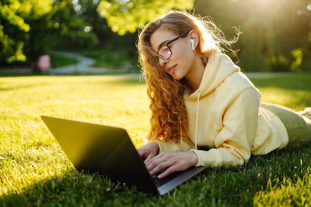 Foto mujer joven sonriente con computadora portátil trabajando en el fondo de la construcción de la ciudad concepto de educación independiente