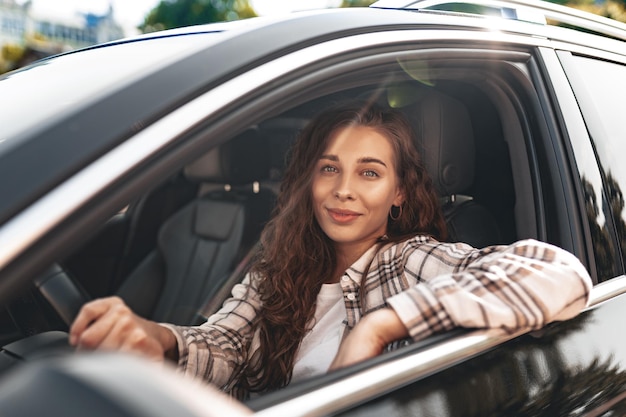 Mujer joven sonriente conduciendo un coche en la ciudad
