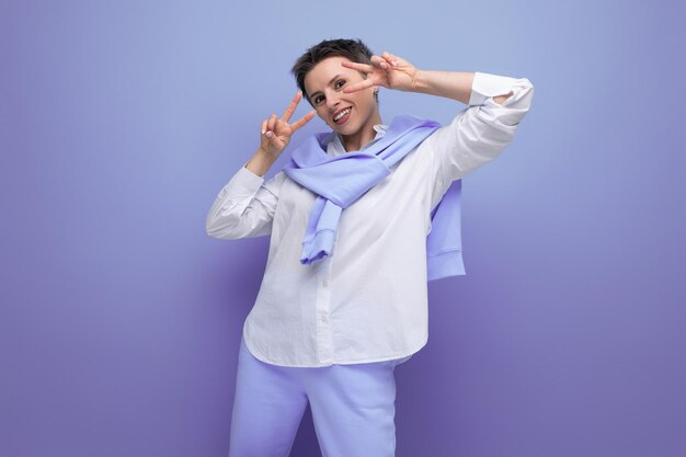 Mujer joven sonriente con corte de pelo corto en camisa blanca y pantalones azules