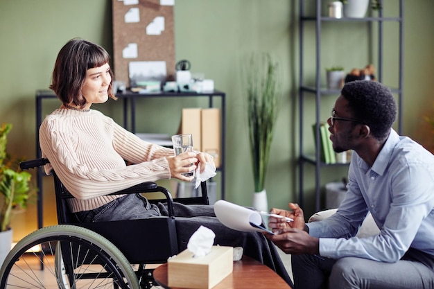 Mujer joven sonriente con discapacidad visitando a su psicóloga para una sesión de terapia semanal