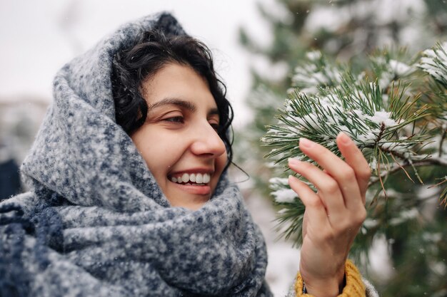 Mujer joven sonriente se encuentra en un parque de invierno cubierto de nieve helada.