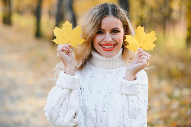 Mujer joven sonriente feliz en el parque el día de otoño