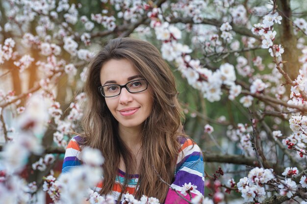 Mujer joven sonriente en el floreciente jardín de primavera