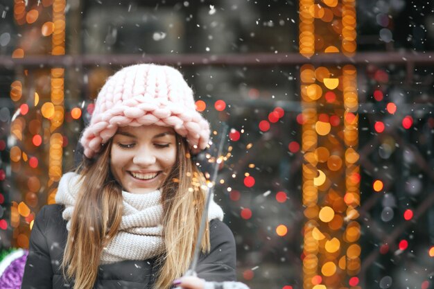 Mujer joven sonriente jugando con luces brillantes en la calle. Espacio vacio