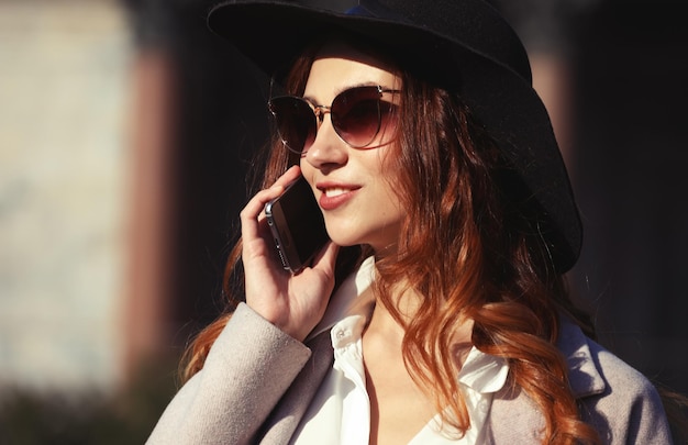 Mujer joven sonriente llamando y hablando por teléfono inteligente