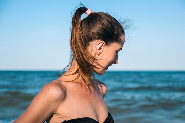 Mujer joven sonriente en el mar mira hacia un lado.