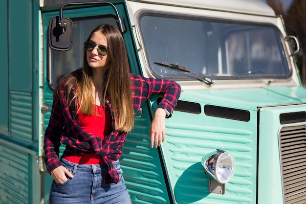 Mujer joven sonriente por la minivan vintage