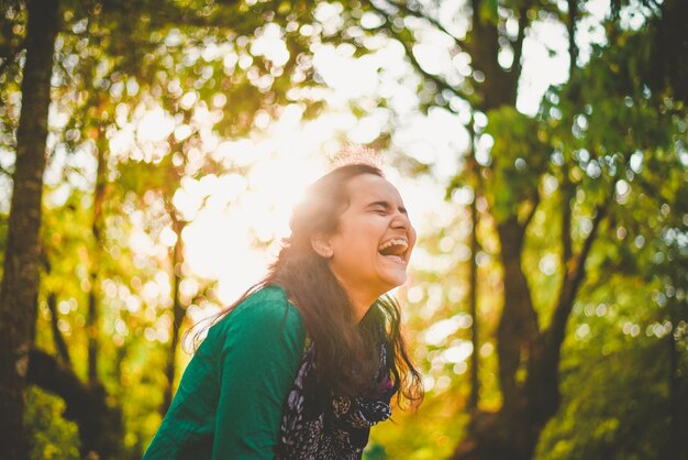 Foto mujer joven sonriente mirando hacia los árboles