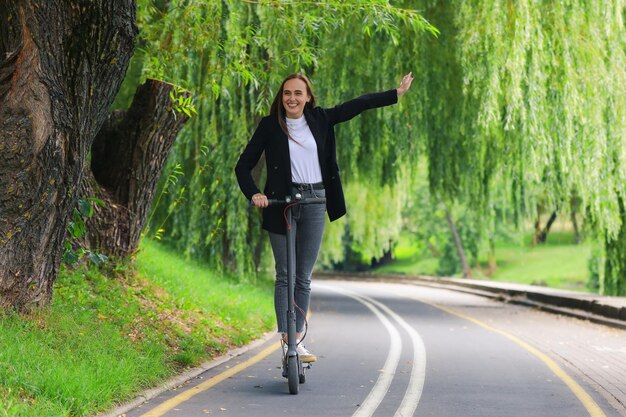 Una mujer joven sonriente monta un scooter eléctrico Ecotransport Entorno urbano