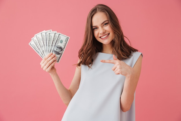 Mujer joven sonriente mostrando dinero apuntando.