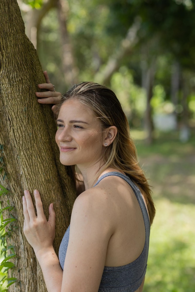 Foto una mujer joven sonriente en un parque en un hermoso día soleado una mujer abrazando un árbol verde y la naturaleza