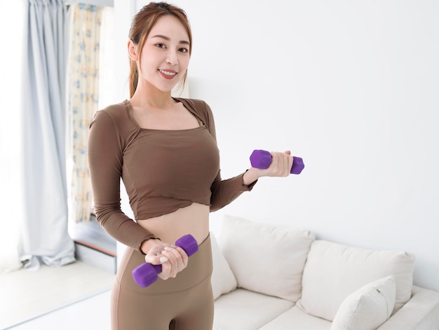 Mujer joven sonriente con pesas haciendo ejercicio en casa