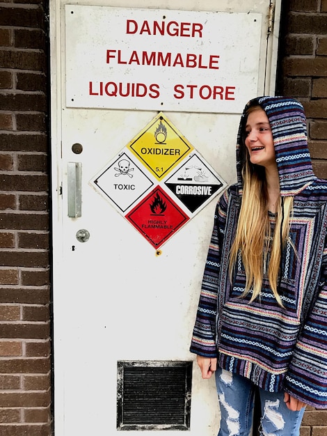 Foto una mujer joven sonriente de pie mientras mira el cartel de advertencia en la puerta