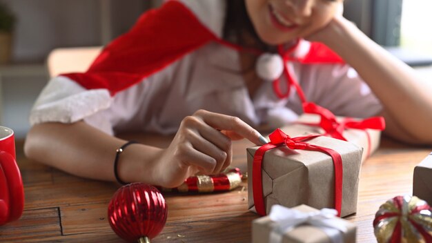 Mujer joven sonriente preparando regalos para Navidad.