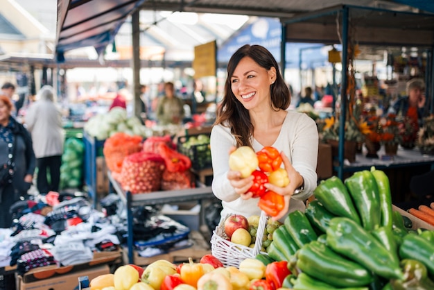 Mujer joven sonriente que compra verduras frescas.