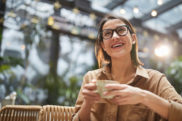 Foto mujer joven sonriente que goza del café en café