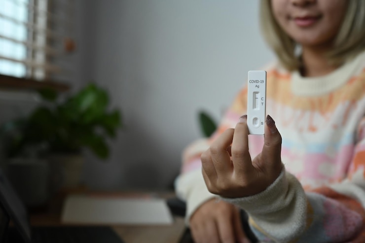 Foto mujer joven sonriente que muestra el kit de prueba del antígeno covid 19 con resultado negativo.